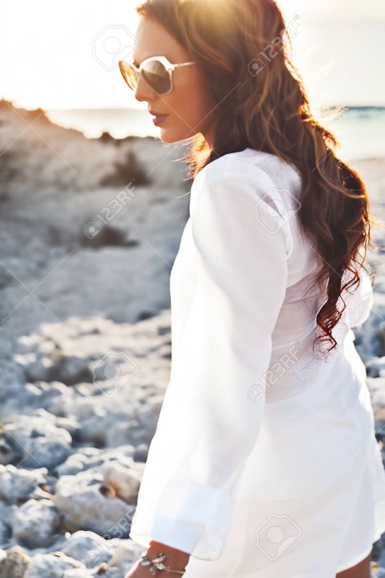 Beautiful boho styled girl wearing white shirt with flash tattoo at the beach in sunlight