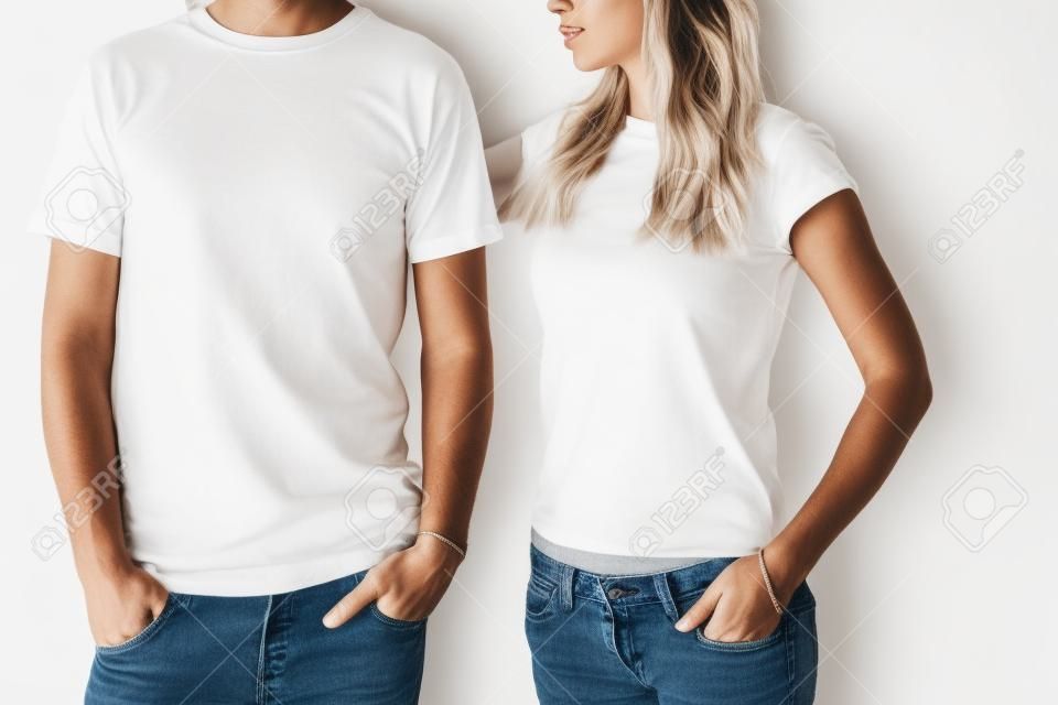 Twee hipster modellen man en vrouw dragen blanc t-shirt, jeans en zonnebril poseren tegen witte muur, toned foto, front tshirt mockup voor koppel