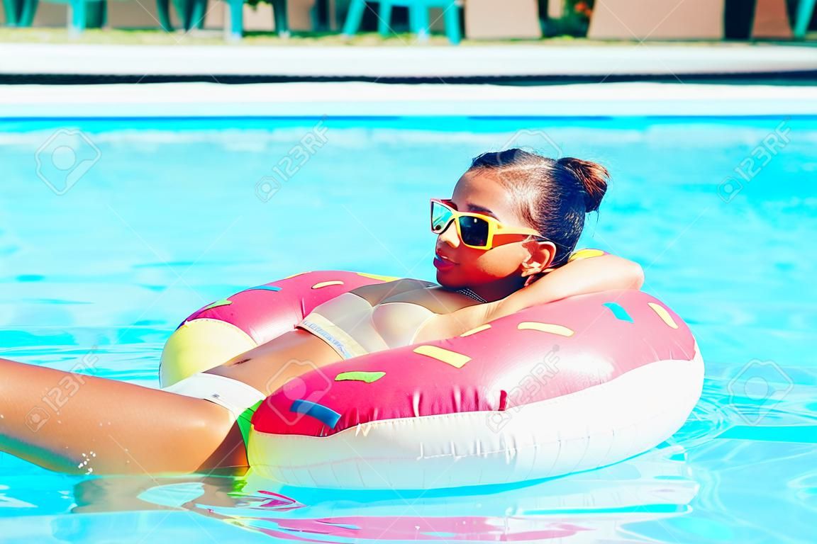 Tween girl relaxing on the donut lilo in resort pool in Thailand