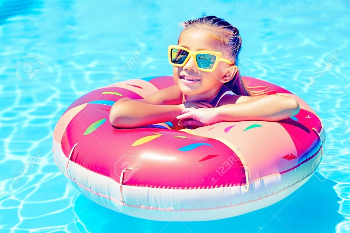 Tween girl relaxing on the inflatable ring in resort pool in Thailand