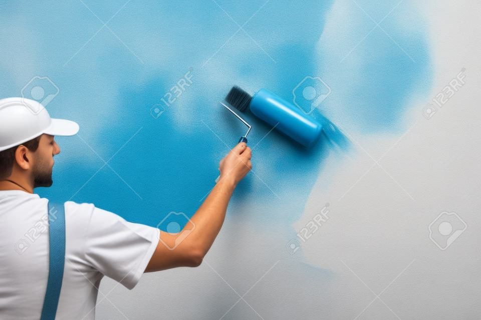 복사 공간이있는 페인트 롤러로 벽을 칠하는 화가의보기