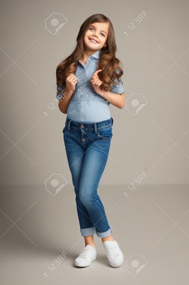 cute little girl posing in shirt and jeans in studio