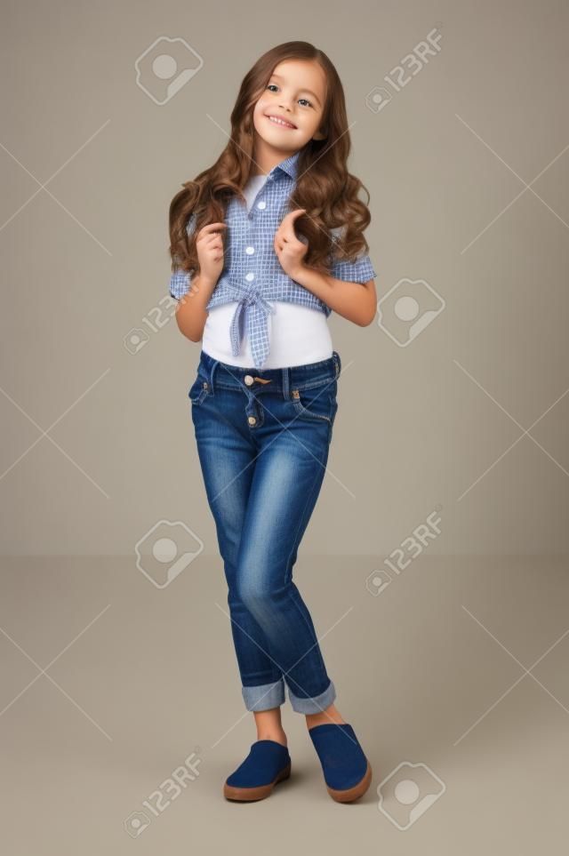 cute little girl posing in shirt and jeans in studio