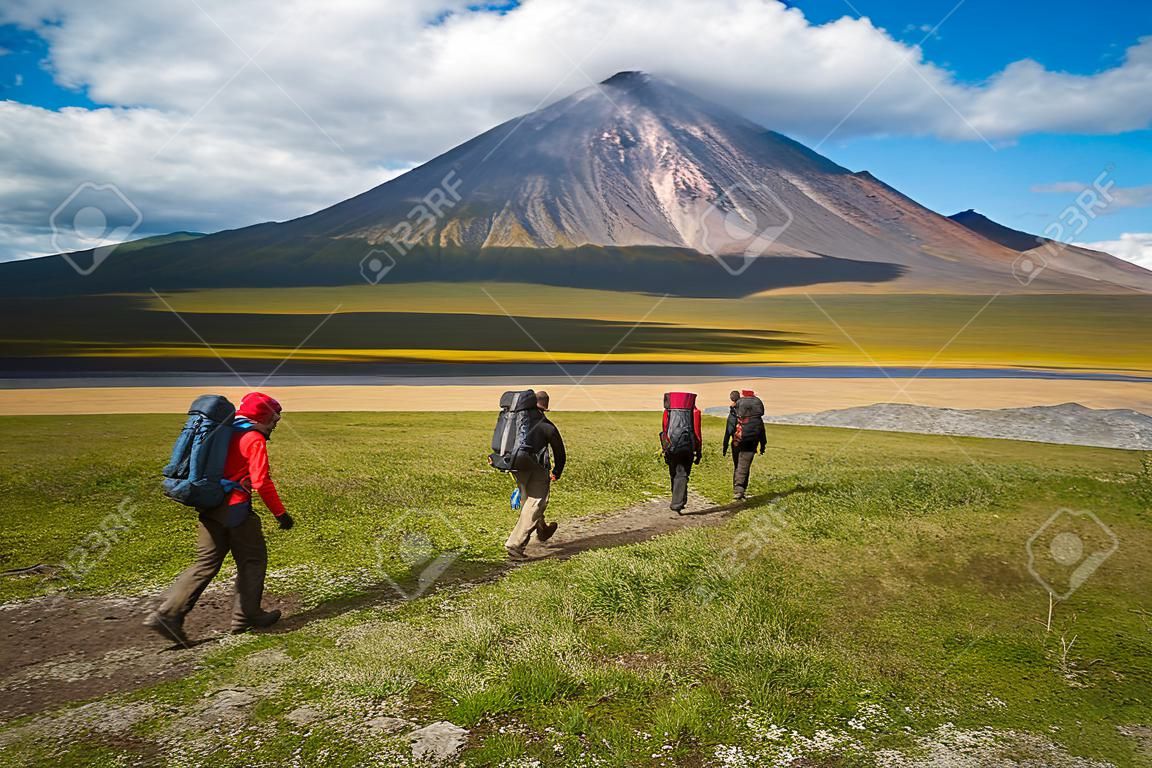 Hikers moving on volcano land in Kamchatka, Russia.