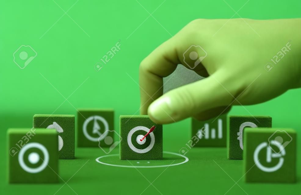 Hand putting target board with arrow on green background to setup objective target and investment goal.