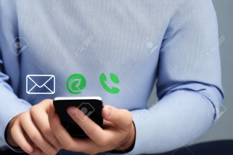 O homem de negócios que usa o smartphone para contato comercial da página da Web inclui o endereço de e-mail e o número de telefone.