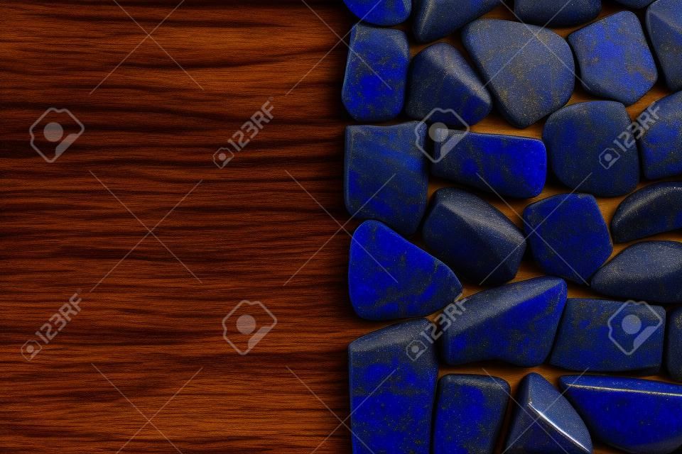Lapis lazuli jewel stone texture on brown varnished wood background. Macro closeup.