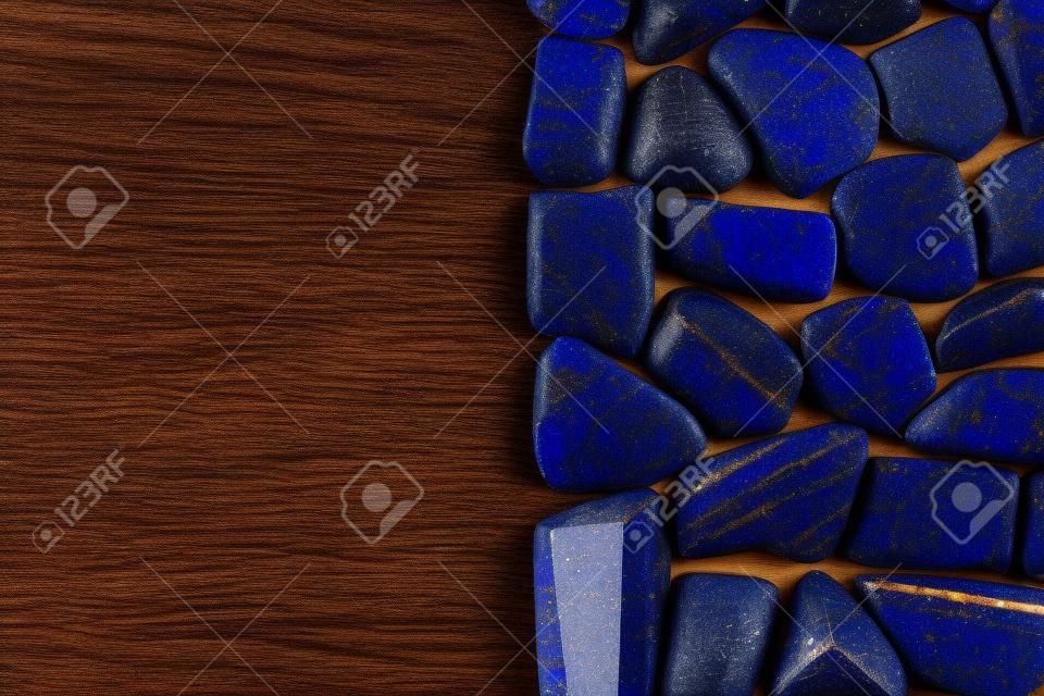 Lapis lazuli jewel stone texture on brown varnished wood background. Macro closeup.