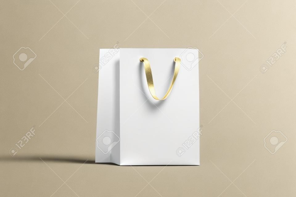 Blank white paper gift bag with gold silk handle mockup, 3d rendering. Empty shopping packet mock up, isolated. Clear plastic bag for purchase or present. Beautiful craft package template.