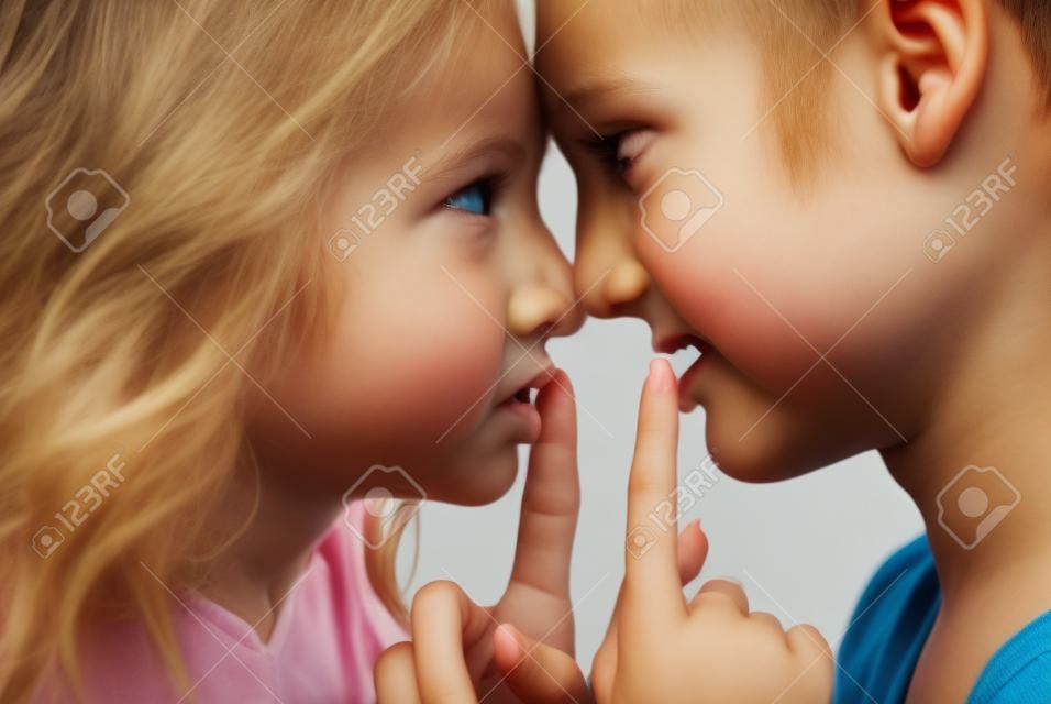 Garçon et fille debout face à face avec les doigts sur leurs lèvres.