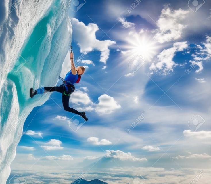 Elegant female athlete hanging at top of dangerous peak equipped with gear rope harness blue sky terrific clouds on background and sunbeams shining from above