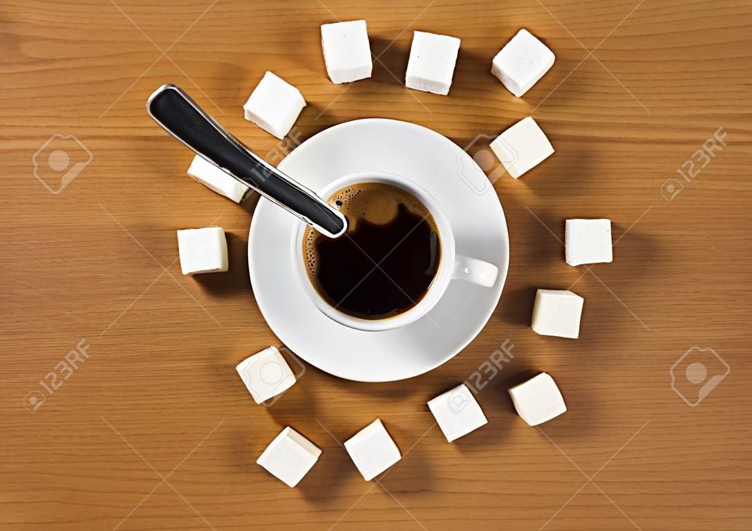 Tasse Kaffee mit Untertasse und Zucker wie eine Uhr auf einem hölzernen braunen Tisch, Ansicht von oben