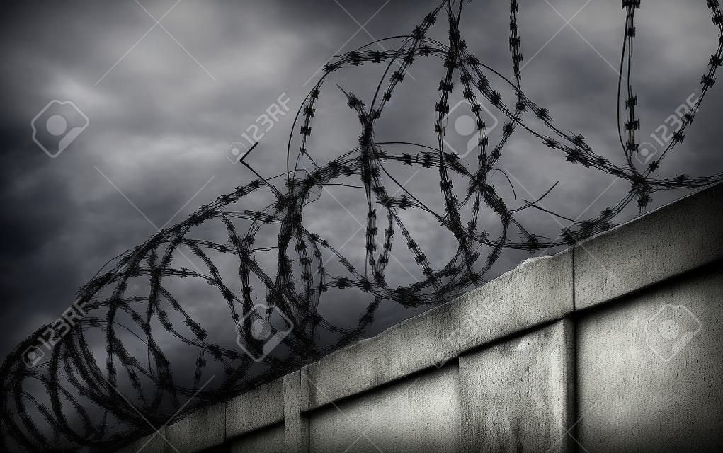 Concrete wall with barbed wire on the fence