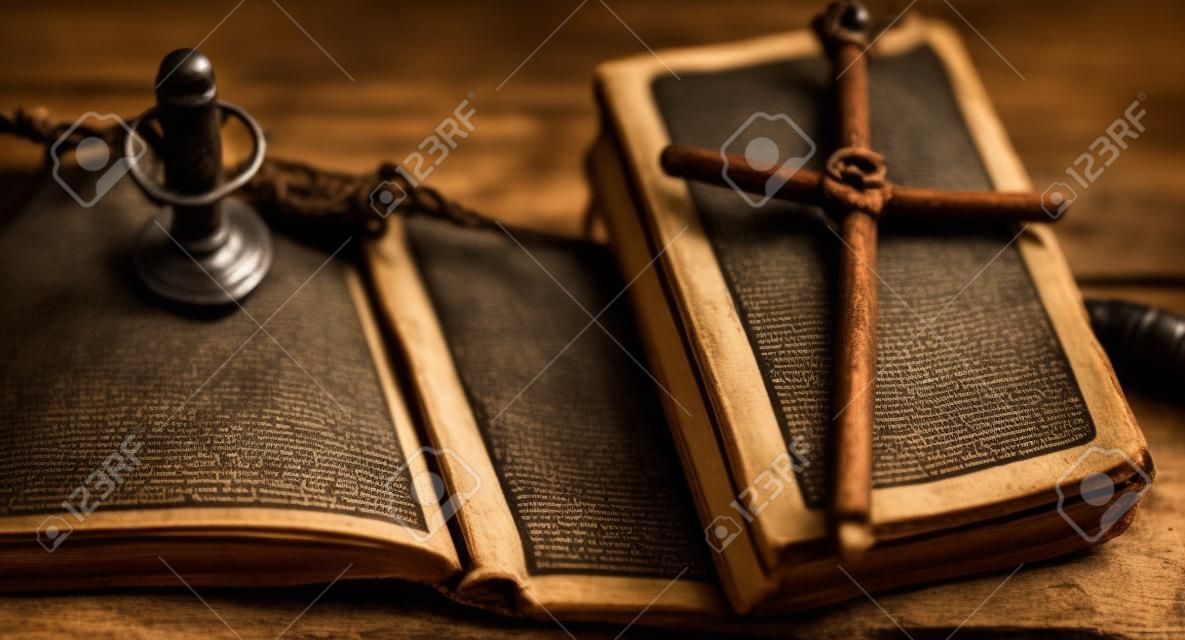 Libro antiguo religioso sobre una mesa de madera. Una cruz religiosa atada ingenio