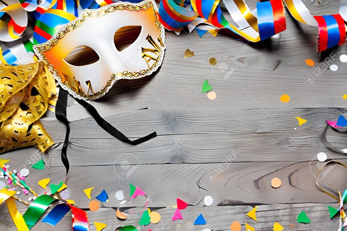 Fondo carnaval de colores con guirnaldas, streamer, sombreros de fiesta, confeti y máscara