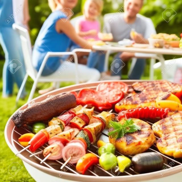 夏天在花园里举行烧烤聚会的家庭