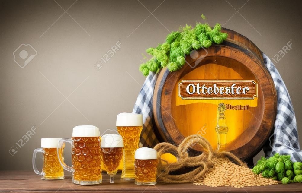 Oktoberfest barril de cerveza y vasos de cerveza con trigo y saltos en la mesa de madera