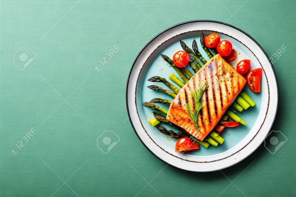 烤三文鱼饰以绿色芦笋和西红柿。顶视图