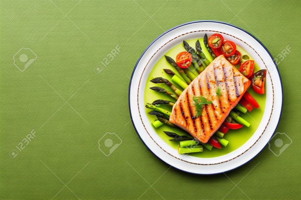 烤三文鱼饰以绿色芦笋和西红柿。顶视图