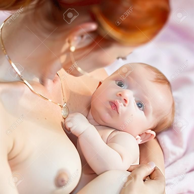 Breastfeeding. Red haired mother holding newborn baby and breastfeed