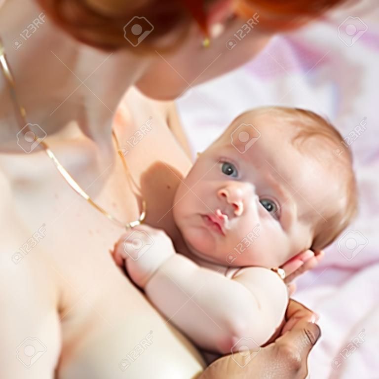 Breastfeeding. Red haired mother holding newborn baby and breastfeed