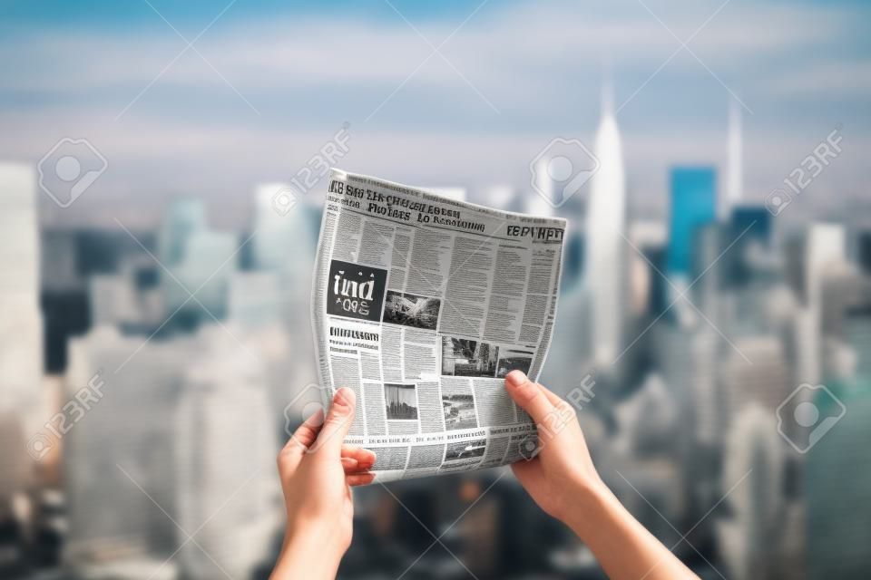 A hand holding a newspaper in front of a city skyline, with a blurred background. The focus is on the newspaper, which appears crisp and clear. Generative AI