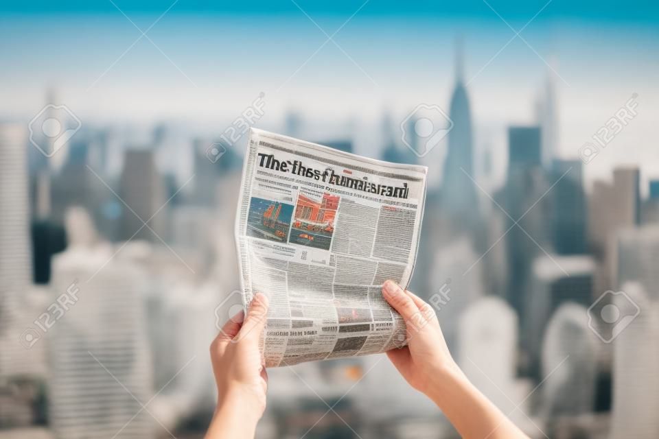 A hand holding a newspaper in front of a city skyline, with a blurred background. The focus is on the newspaper, which appears crisp and clear. Generative AI