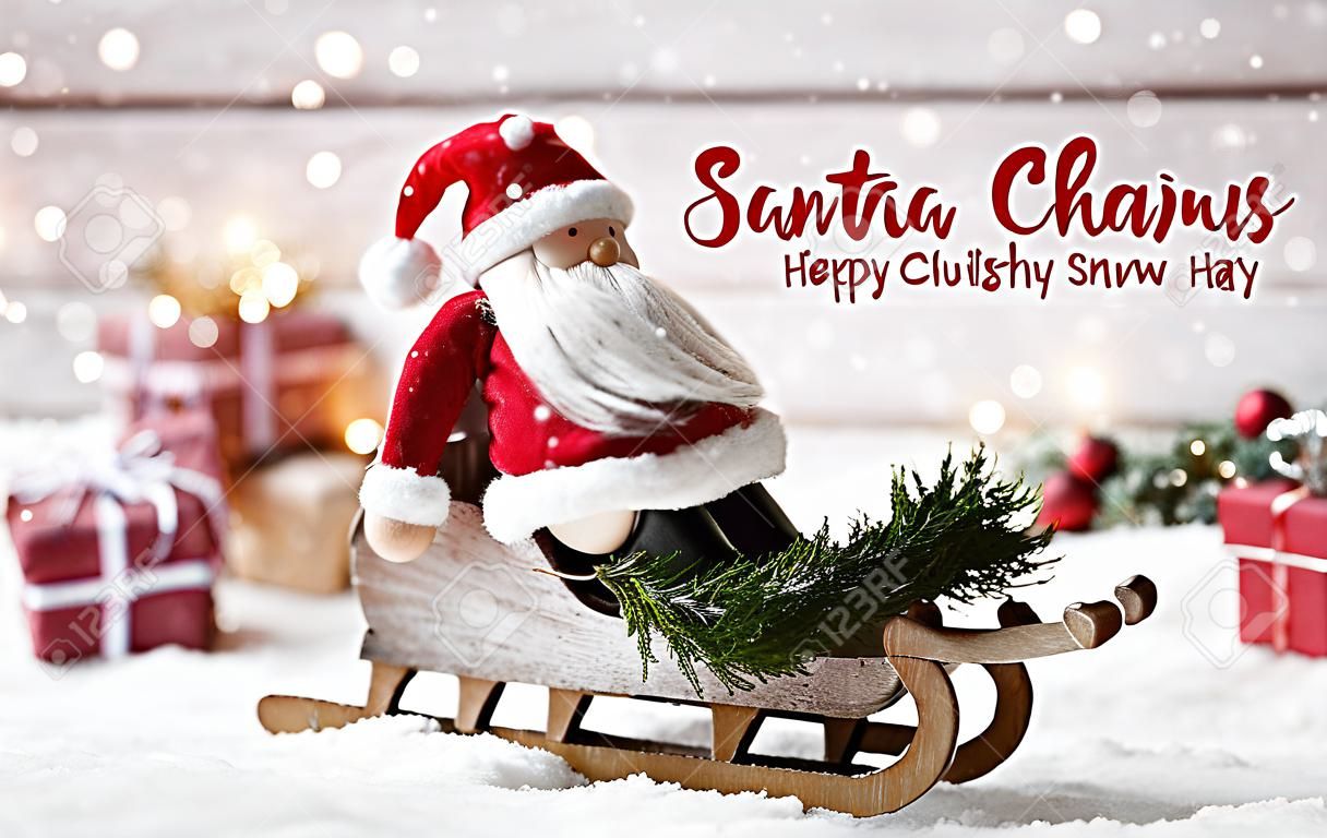 Netter Weihnachtsmann auf einer Schlittenfahrt - Winterszene mit Holzhintergrund, Schnee und vielen Weihnachtsgeschenken