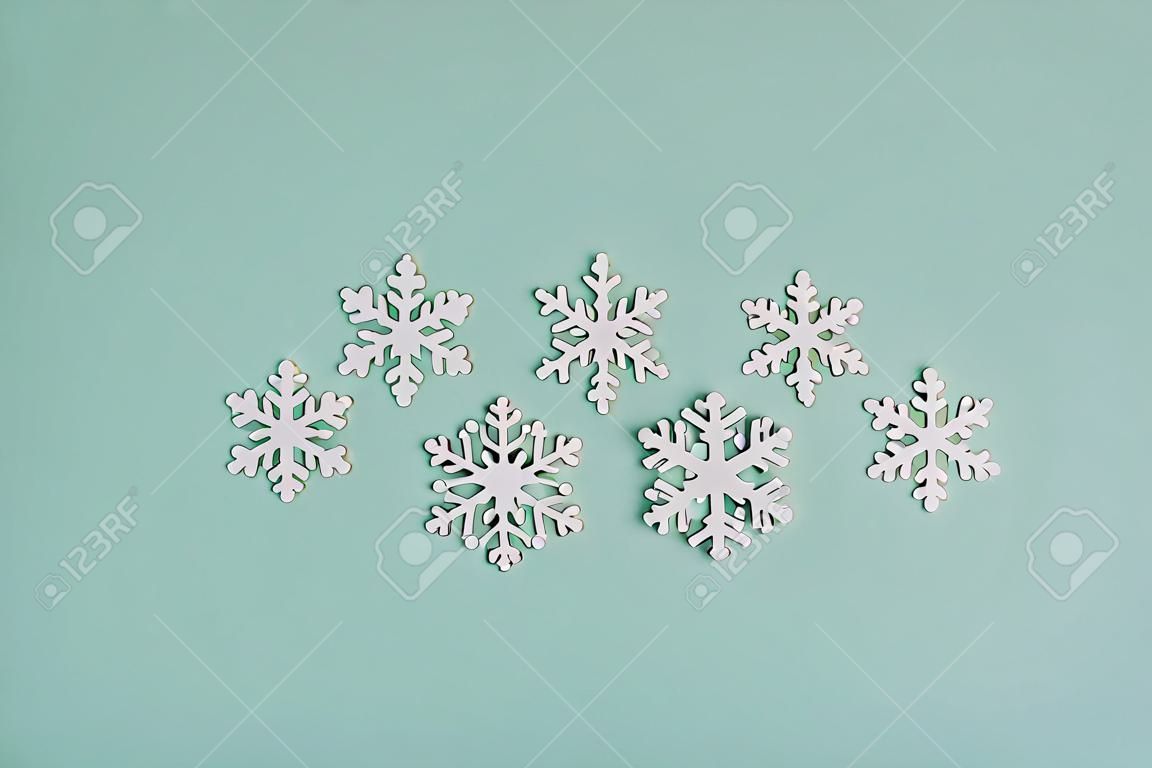 Flocons de neige en bois blancs sur fond clair. Des flocons de neige sont disposés sur un fond couleur menthe en forme de sapin de Noël.