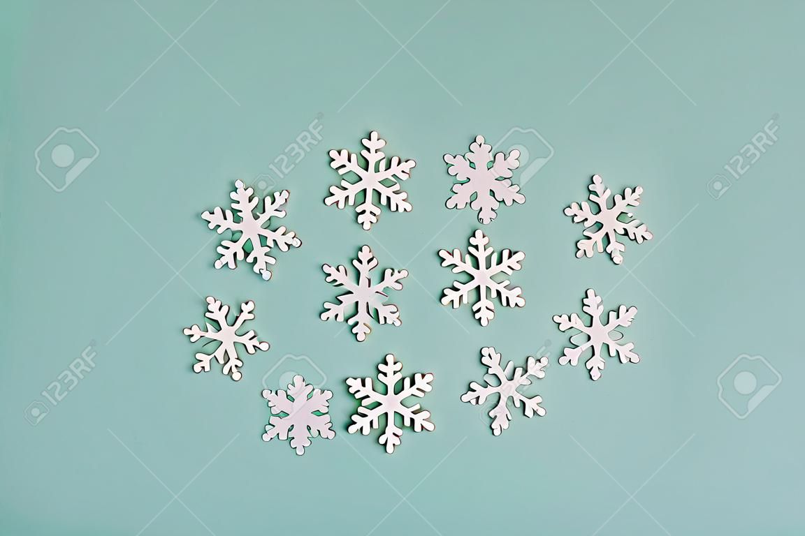 Flocons de neige en bois blancs sur fond clair. Des flocons de neige sont disposés sur un fond couleur menthe en forme de sapin de Noël.