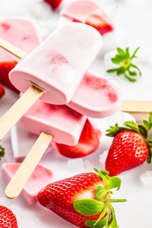 Zelfgemaakte ijslolly's met yoghurt of ijs met aardbeien