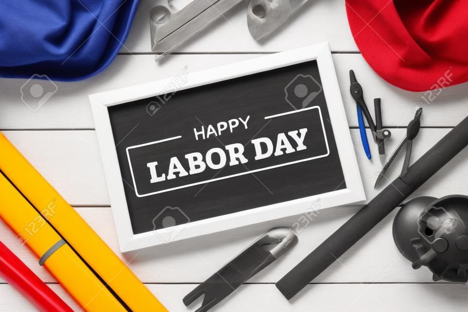 Happy Labor Day text on chalkboard with construction tools on white wooden background