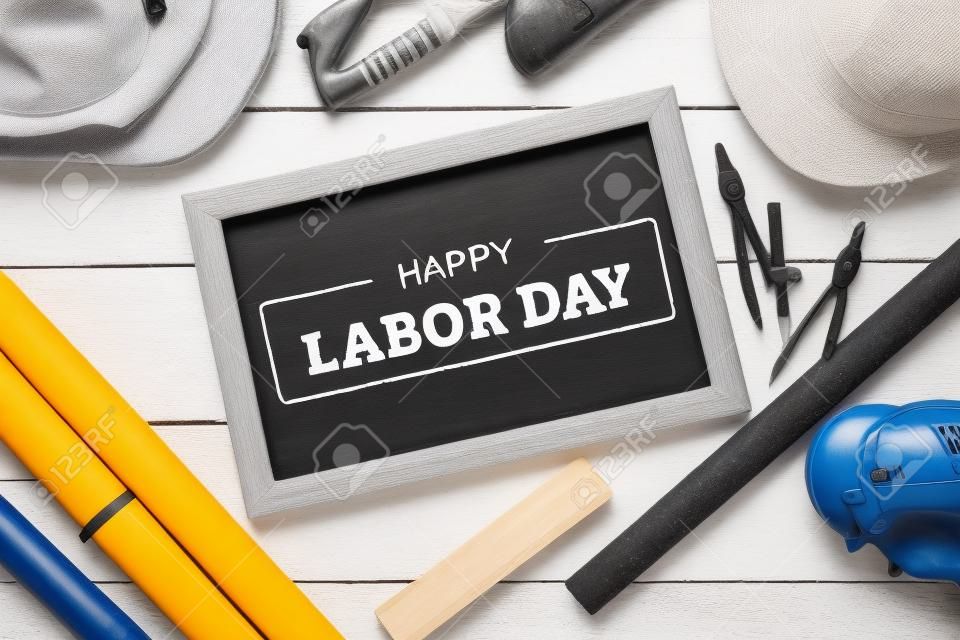 Happy Labor Day text on chalkboard with construction tools on white wooden background