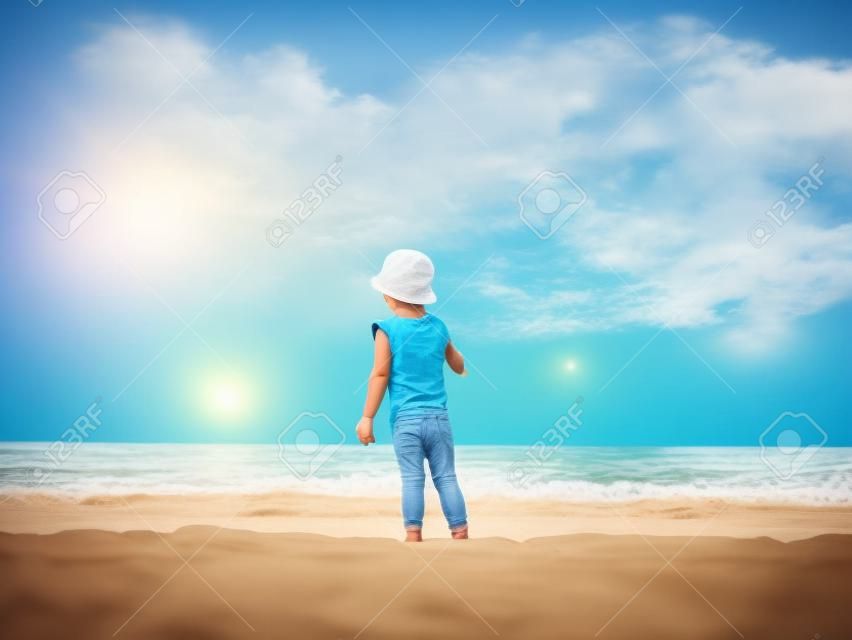 Маленький мальчик смотрит на океан, летом играет на берегу моря. Ребенок веселится с песком. Концепция летнего отдыха. Концепция счастливого детства