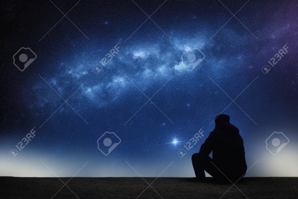 A csillag néző ember. Egyedülálló ember nézi a csillagos ég. Éjszakai égbolt.