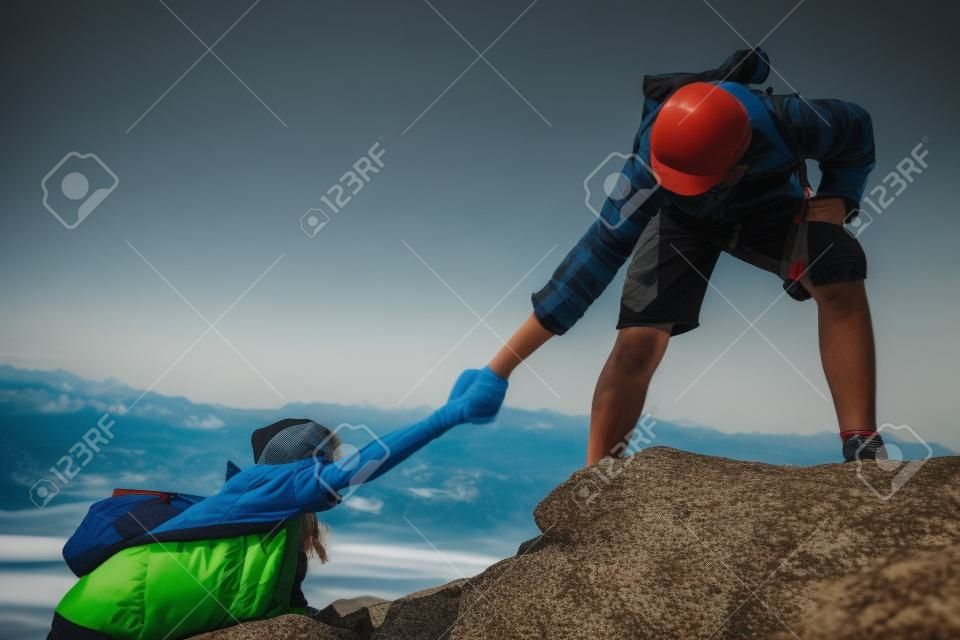 niño ayudando a una niña en la cima de la montaña en la naturaleza