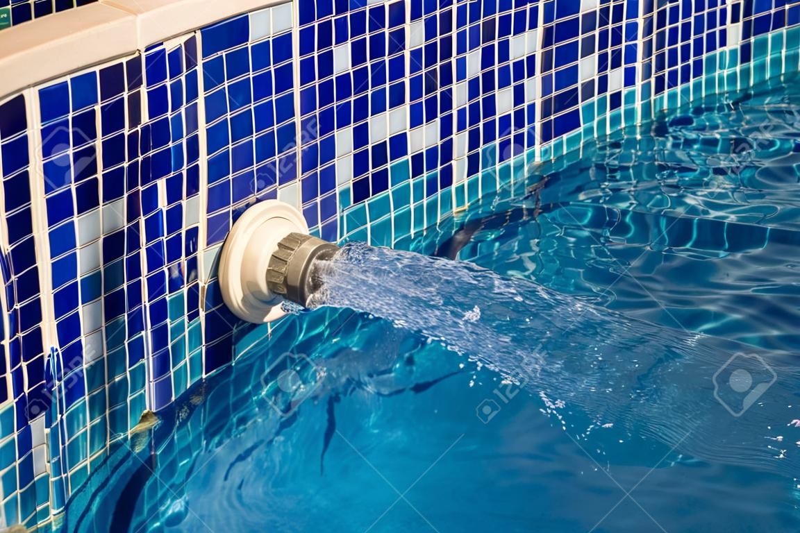 Detailweergave van een instromende waterstraal in een zwembad met blauwe tegels