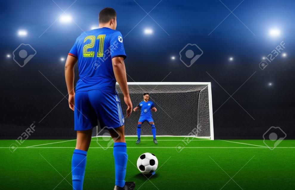 Scena piłki nożnej w nocnym meczu z graczem w niebieskim mundurze kopiącym rzut karny