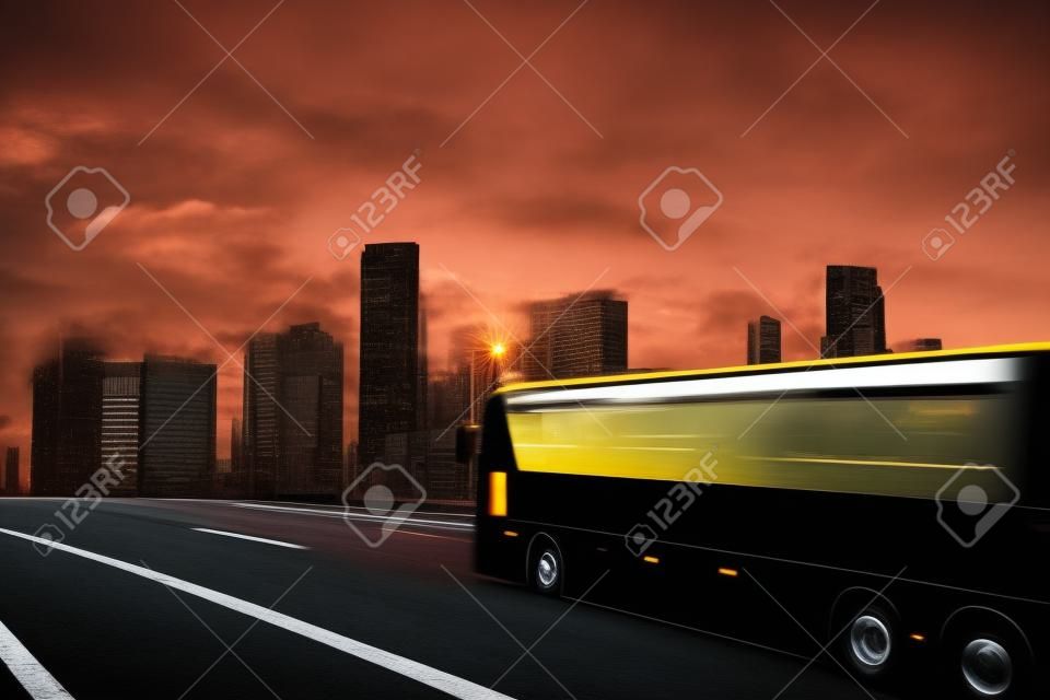 Black bus moving on the road in a cityscape at sunset