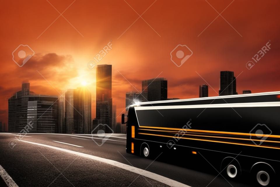 Black bus moving on the road in a cityscape at sunset