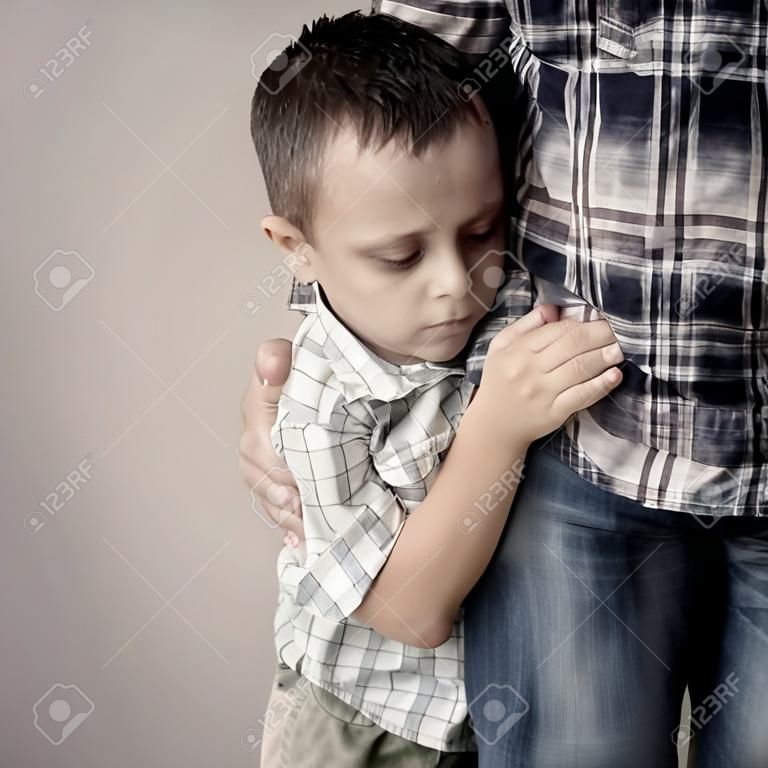 낮 시간에 벽 근처에 자신의 아버지를 포옹 슬픈 아들