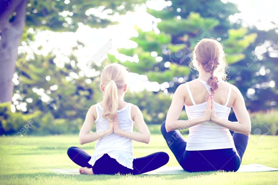 Anya és lánya jóga gyakorlatok fű a parkban, a napos idő