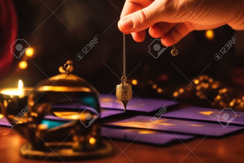 Fortune teller holding a pendulum over tarot cards