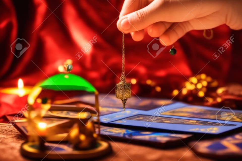 Fortune teller holding a pendulum over tarot cards