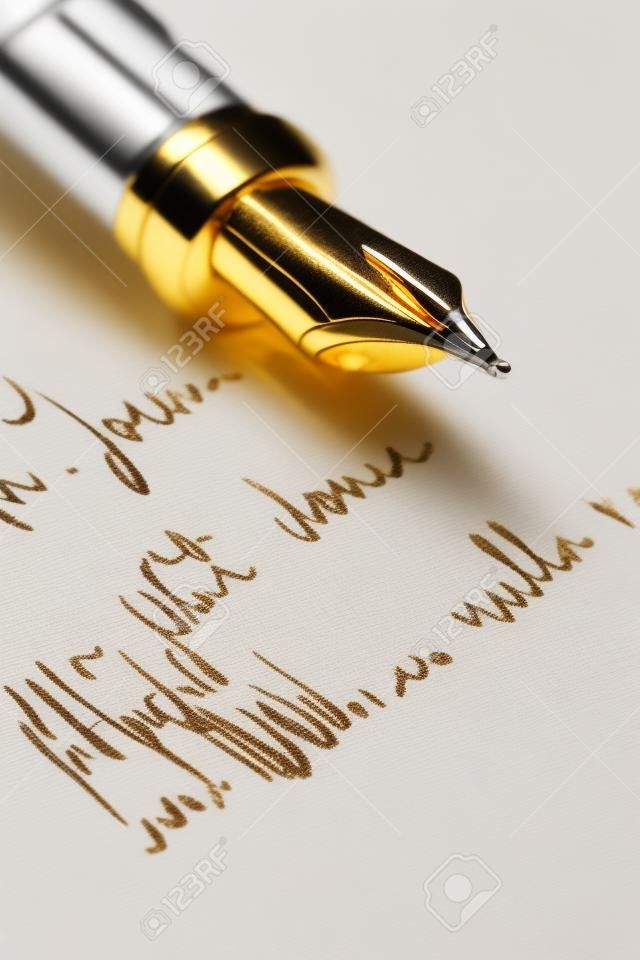 Fuoco selettivo sulla lettera scritta della penna dell'oro sopra mano. Concentrarsi sulla punta del pennino.
