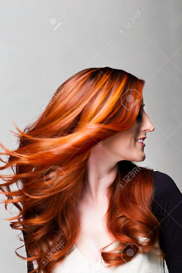 Profil d'une femme rousse frais lancer son magnifique longs cheveux ondulés afin qu'il vole lâche autour de son visage