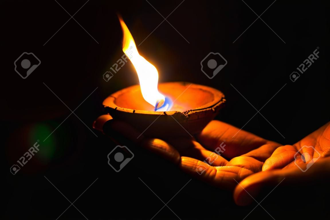 Diya encendida o lámpara de arcilla en la palma de una persona