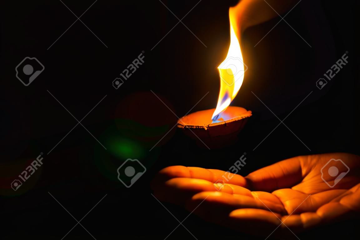 Diya encendida o lámpara de arcilla en la palma de una persona