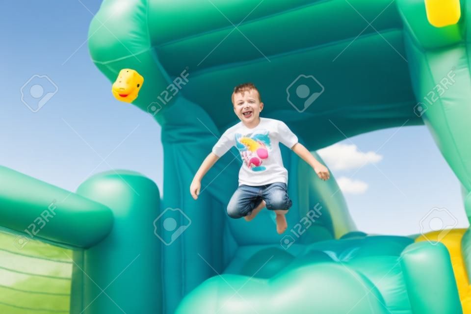 Kleiner Junge, der Spaß auf einer Hüpfburg sprang in die Luft, als er springt aus dem Mund eines Kunststoff hippo