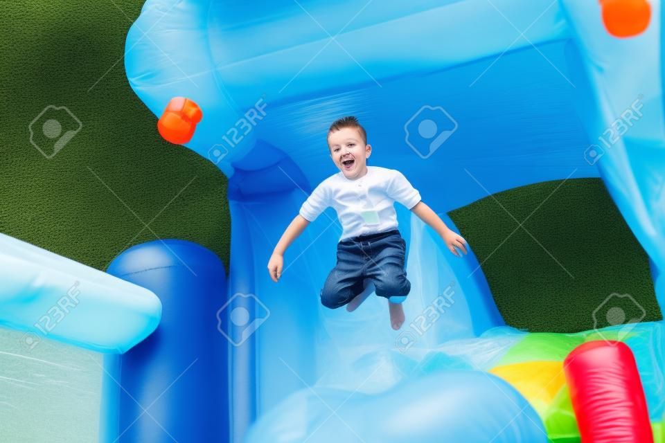 Kleiner Junge, der Spaß auf einer Hüpfburg sprang in die Luft, als er springt aus dem Mund eines Kunststoff hippo